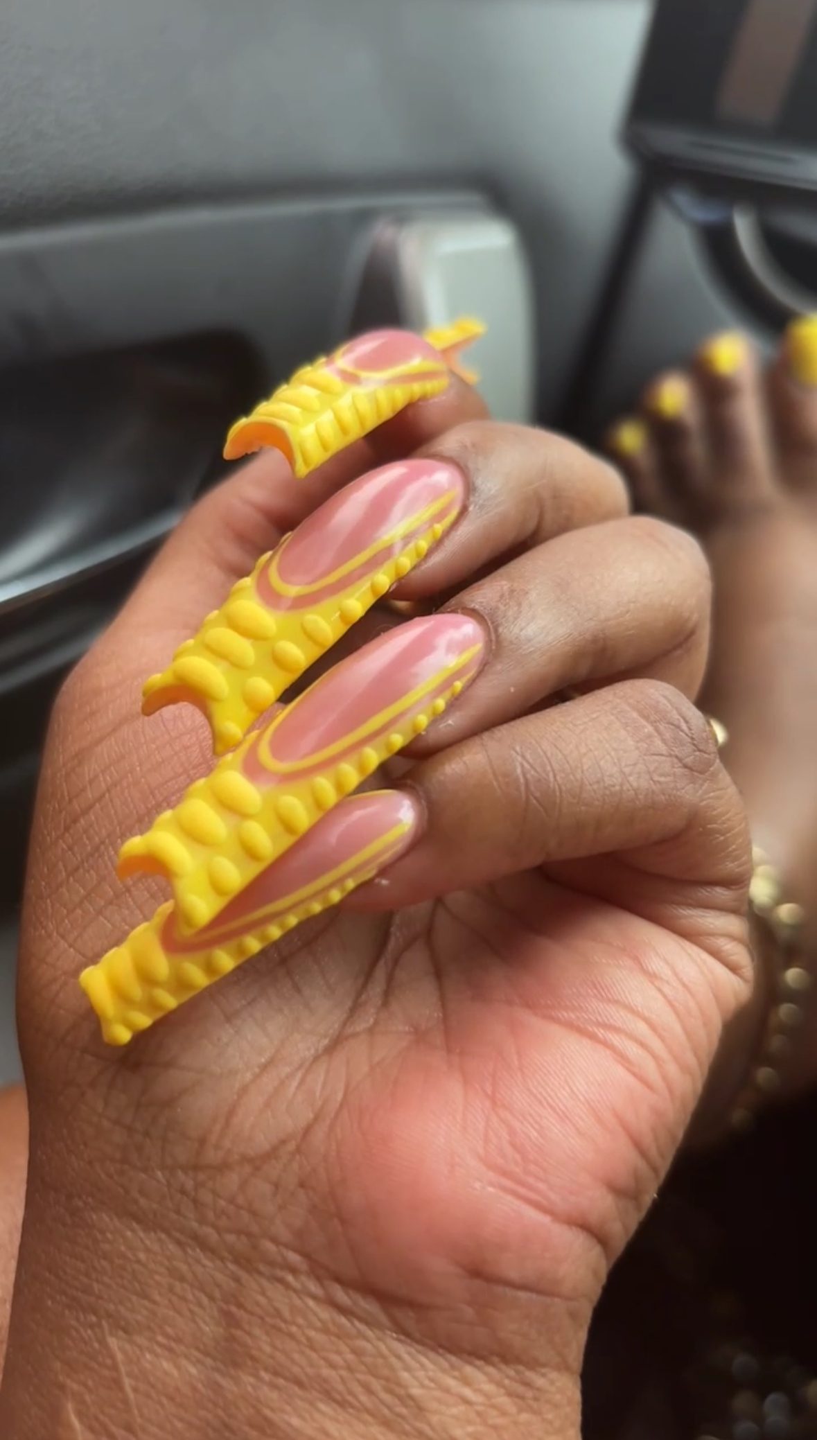 Long yellow sculpted nails with raised 3D detail and matching yellow toes