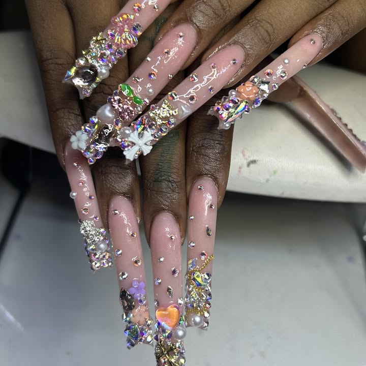 Long pink nails covered in crystals, pearls, bows and charms